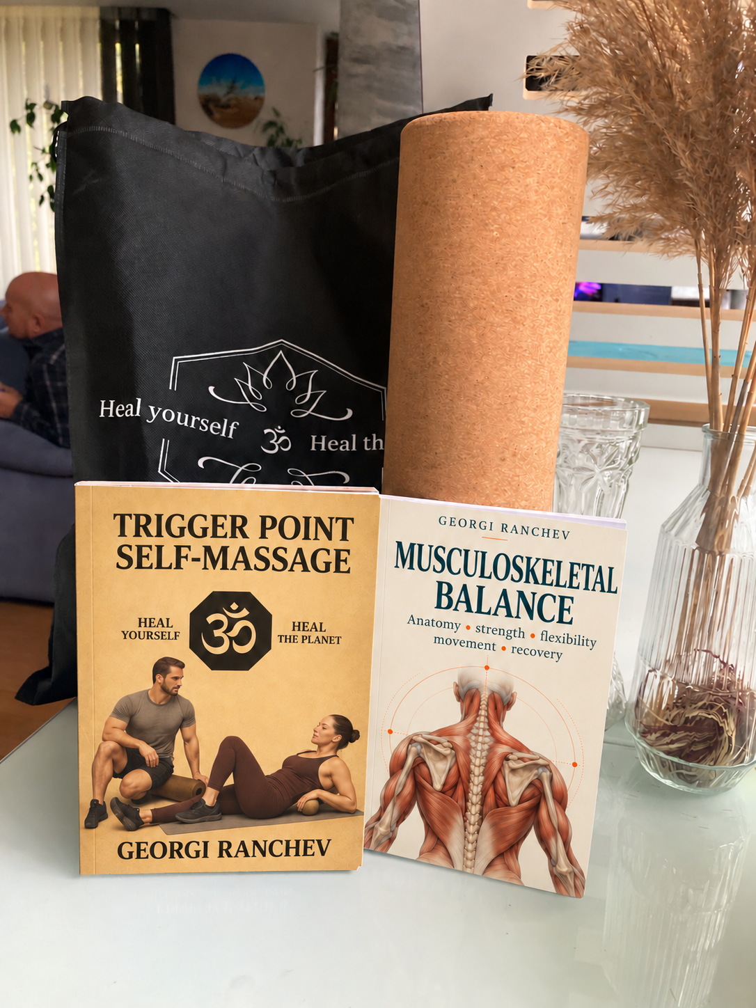 The two books in front of the black storage bag and upright cork roller.
